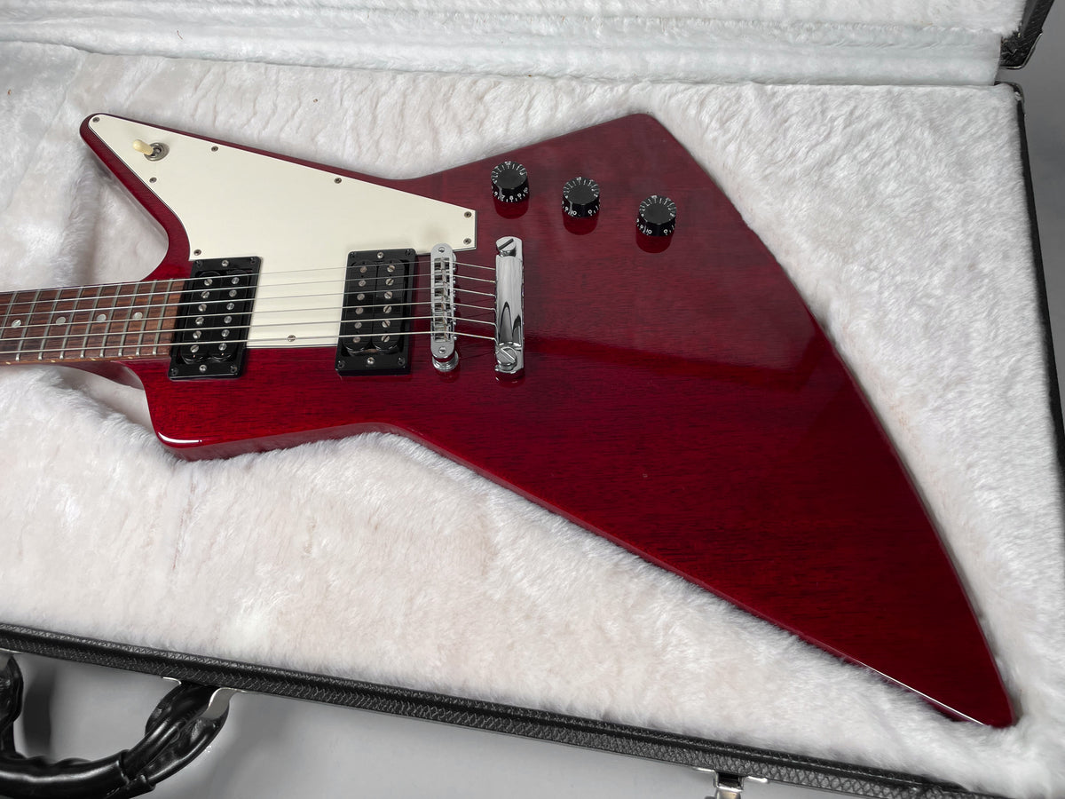 Wine red electric guitar, angled in its white plush-lined hard case, showing its body, white pickguard, and chrome hardware.