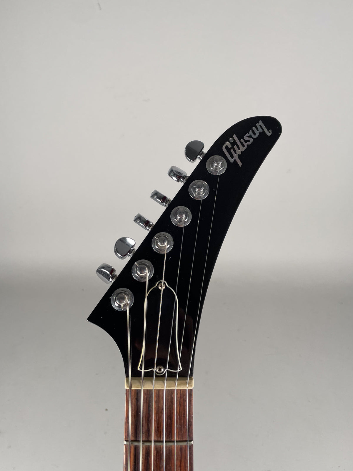 The guitar's black headstock, with six chrome tuners and a bell-shaped truss rod cover, is angled slightly left.