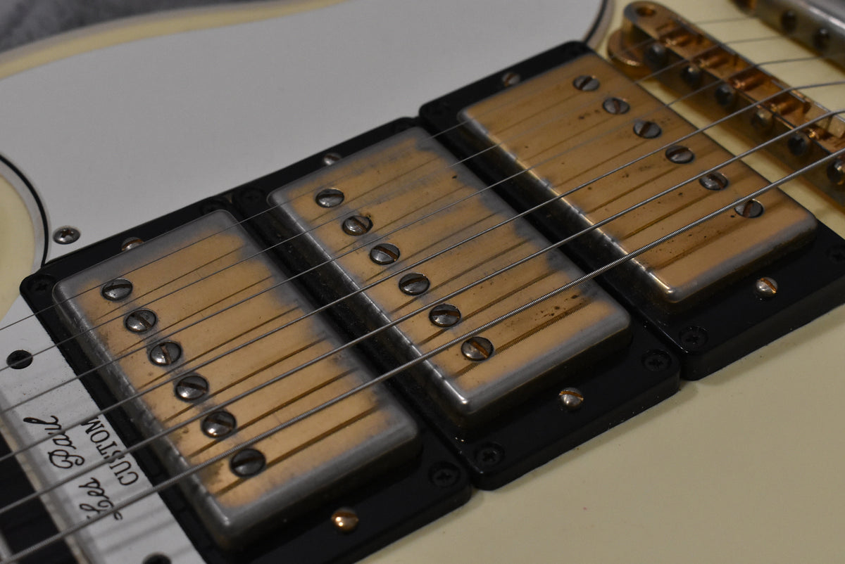 Close-up of the guitar's body, showing two aged gold humbucker pickups with black surrounds and a white pickguard.