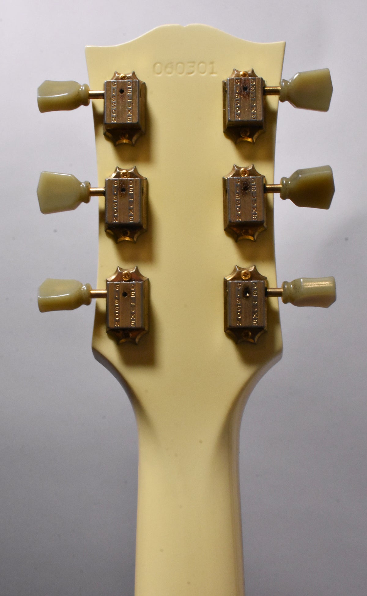 Rear view of the guitar's headstock and upper neck, showing six aged gold tuners with green-tinted plastic buttons.