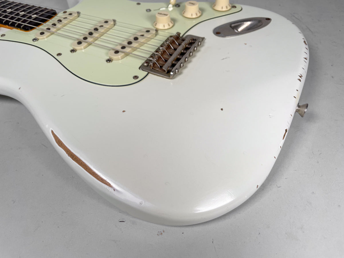 Close-up of the Olympic white body, showing heavy relic wear on the lower bout and edge, with a mint green pickguard.