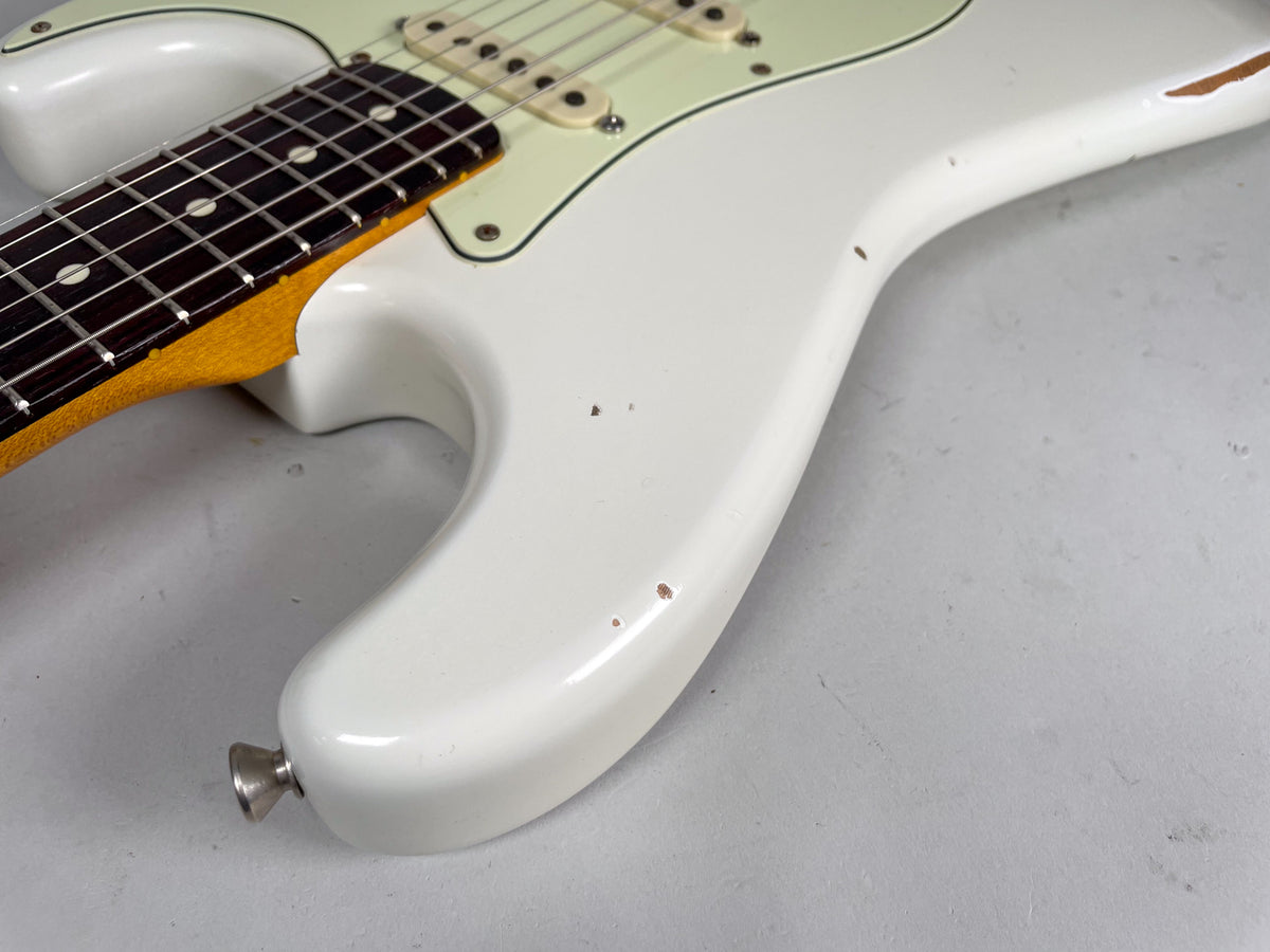 Close-up of the guitar's lower body, showing the Olympic White finish with several chips and wear, and the strap button.