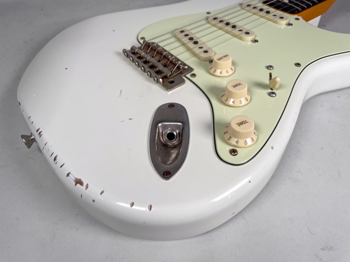 Olympic White relic Strat-style guitar body, showing the input jack, bridge, mint green pickguard, and three cream knobs with wear.