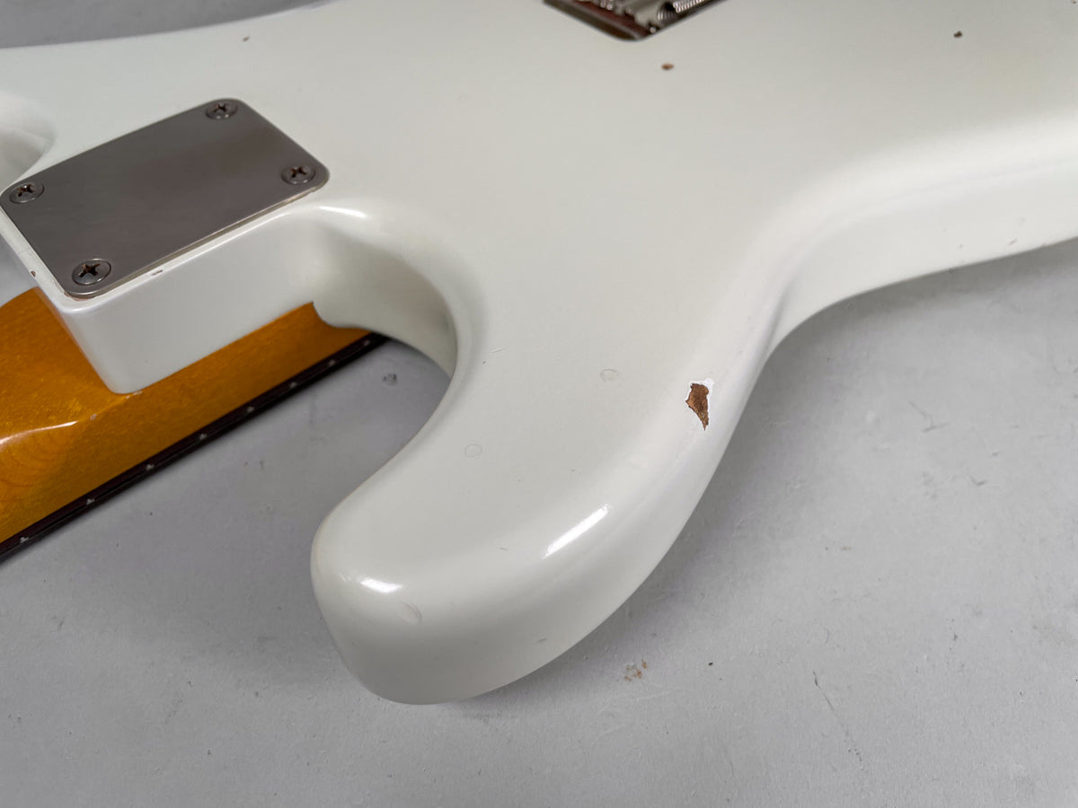 Close-up of the guitar's lower horn and neck joint, showing a large chip in the Olympic White finish revealing the wood beneath.