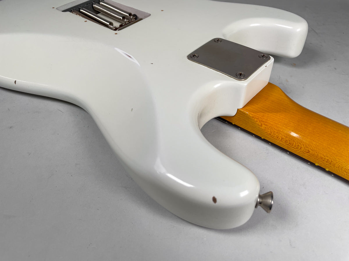 The back of the Olympic white guitar body shows a relic finish, with a few small dark chips and a chrome neck plate.