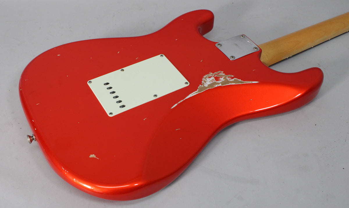 The back of a Candy Tangerine Stratocaster, showing a white tremolo cover, a metal neck plate, and heavy relic wear.