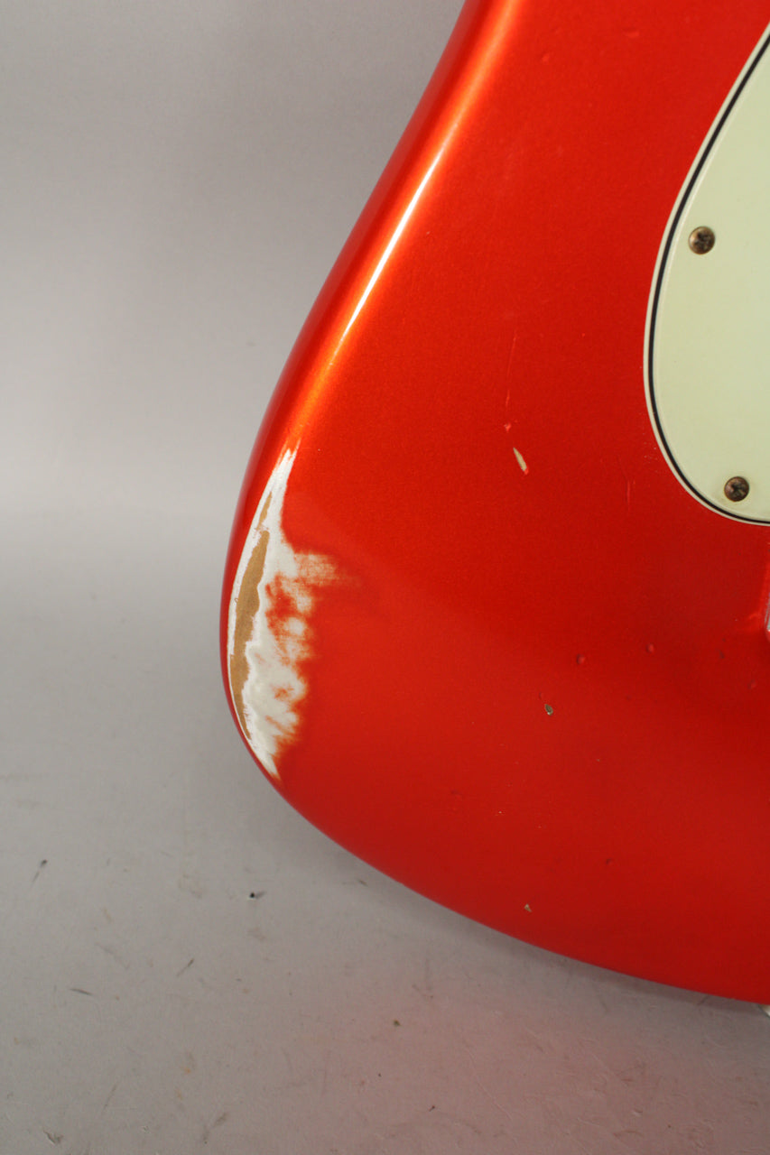 Close-up of the lower bout of the metallic orange guitar body, showing a large area of white and brown finish wear on the edge.