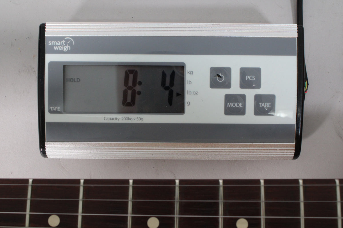 A digital scale displays "8.4" with "HOLD" active, positioned above a dark fretboard with white dot inlays.