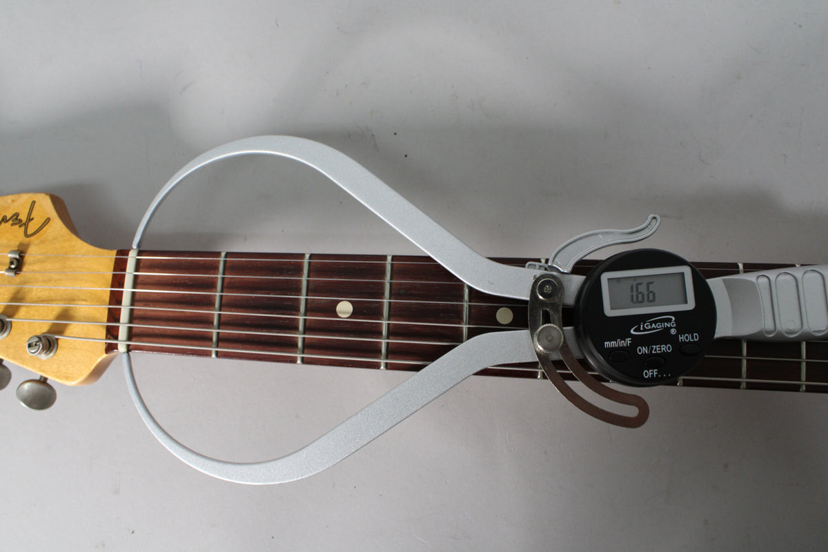 A digital caliper measures the neck relief at 1.66mm, with the headstock and dark rosewood fretboard visible.