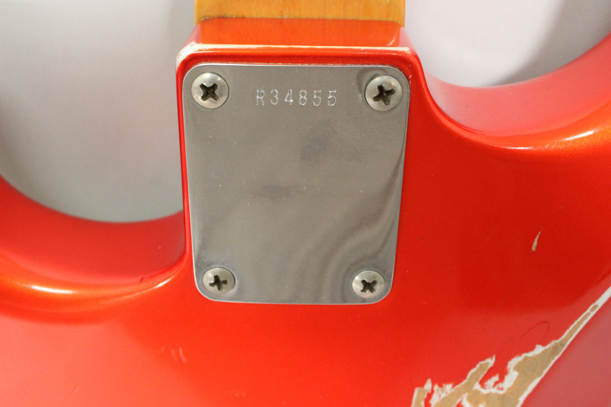 Close-up of the guitar's metallic orange body and neck plate, showing the R34855 serial number and heavy relic wear.