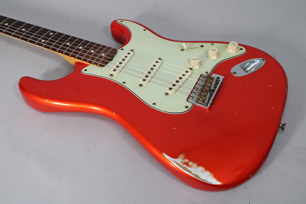 Candy Tangerine Stratocaster body, angled from the neck, with a mint green pickguard, three single-coil pickups, and heavy wear on the lower bout.