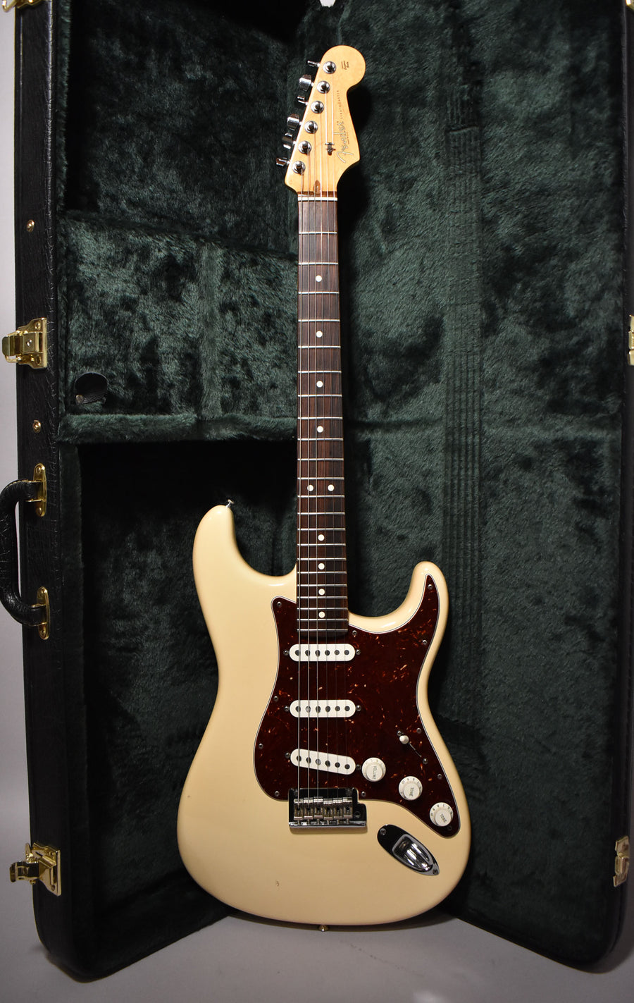 Full-length view of a vintage white Stratocaster with a tortoiseshell pickguard, three single-coil pickups, and a rosewood fretboard.