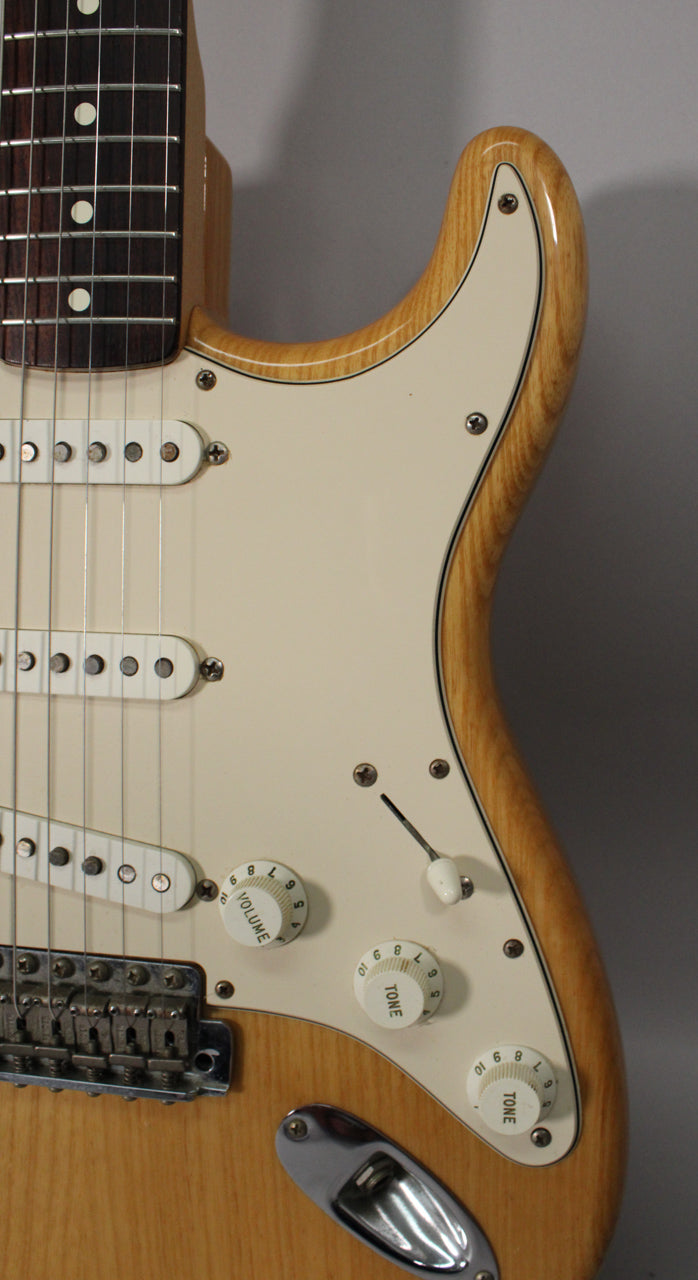 Close-up of the natural finish body and cream pickguard, showing three single-coil pickups, three knobs, and a 5-way switch.