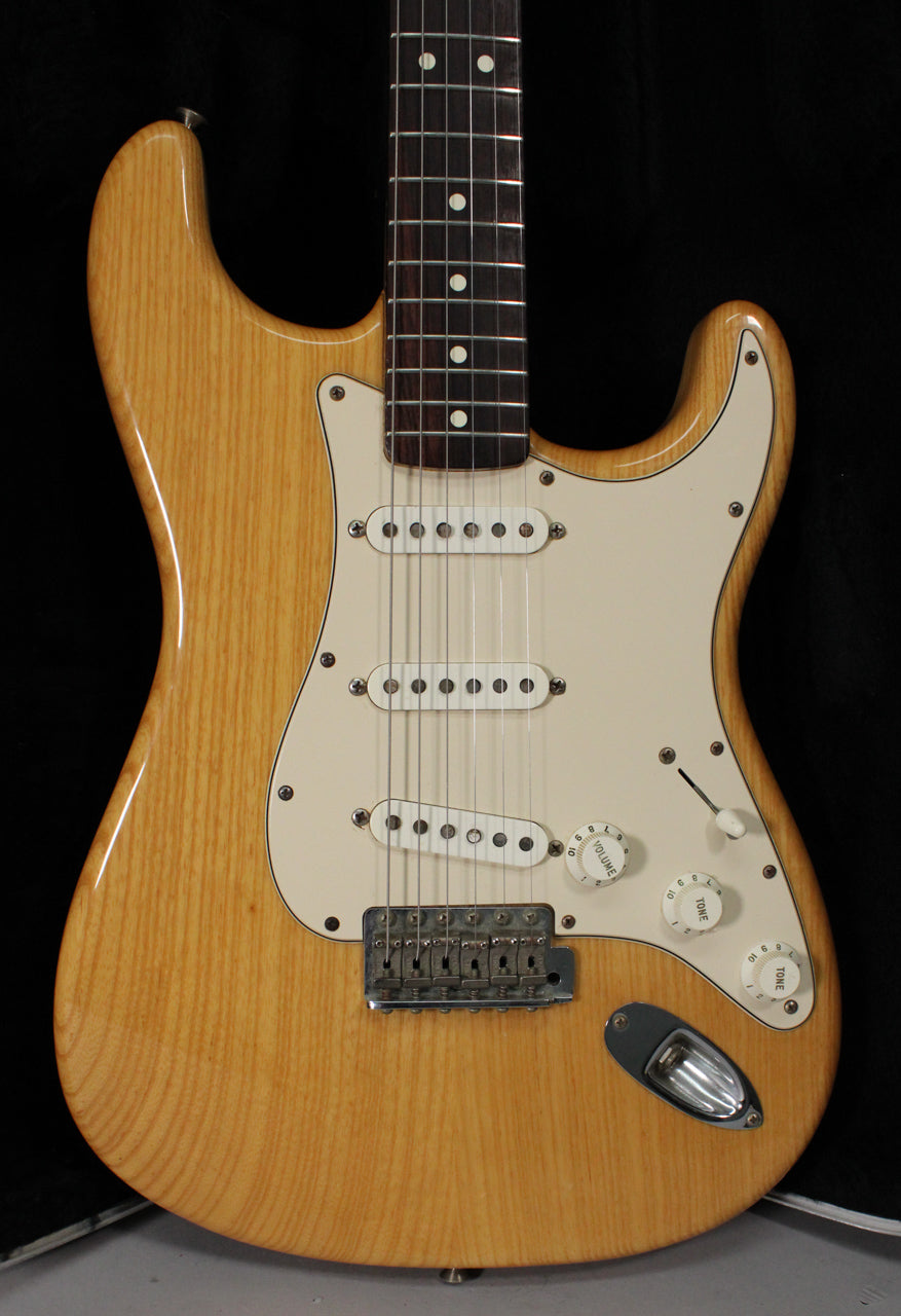 Full front view of a natural wood Stratocaster with a cream pickguard, three single-coil pickups, and a chrome tremolo bridge.