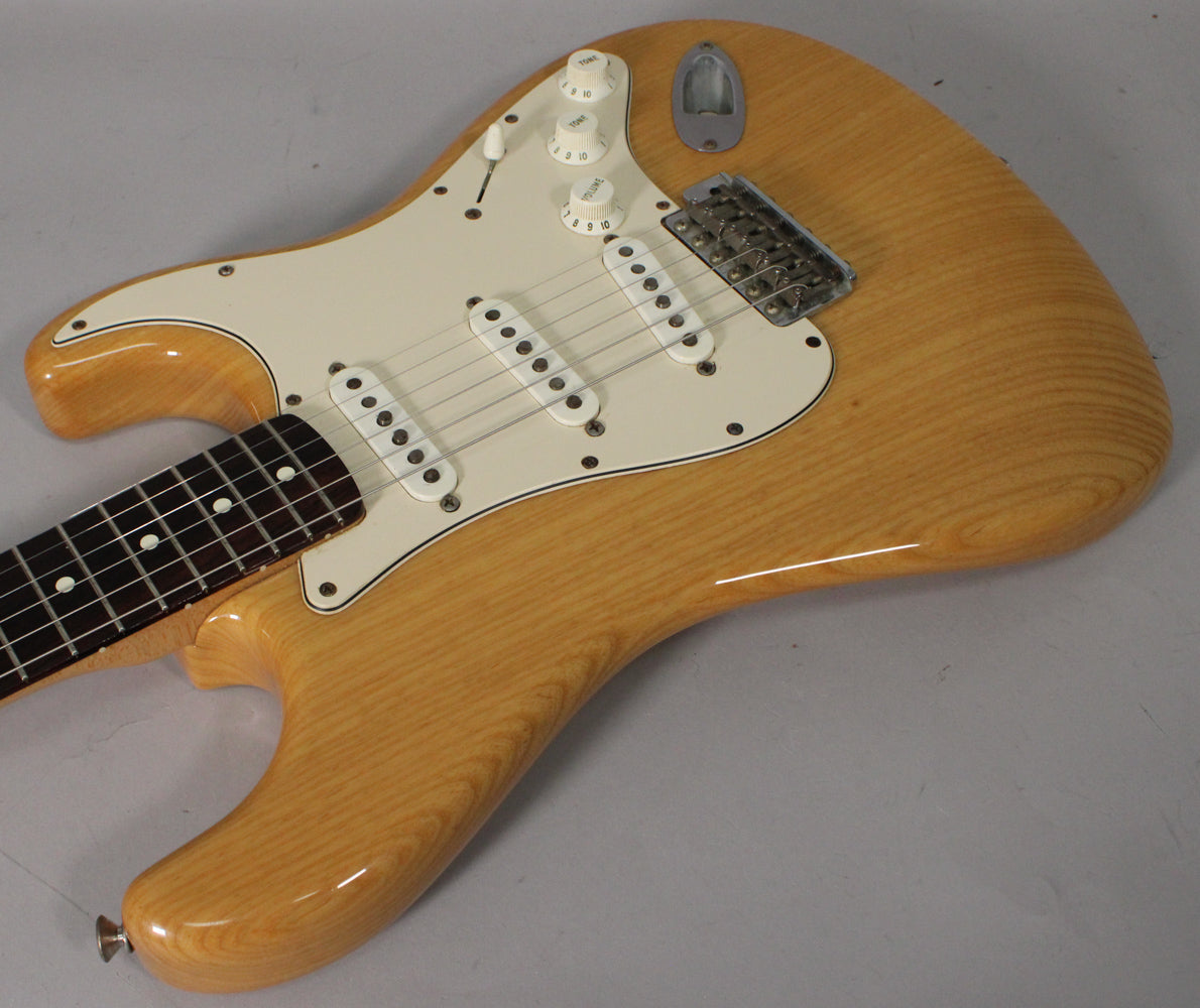 Light blonde Stratocaster body with visible wood grain, white pickguard, three single-coil pickups, and chrome hardware, viewed from above.