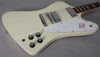 Close-up of the guitar's body, showing the creamy white finish, chrome hardware, white pickguard with red bird graphic, and four black control knobs.