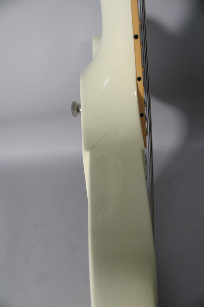 Close-up of the guitar's upper body and neck joint, showing a small scratch on the glossy alpine white finish and a chrome strap button.
