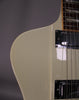 Close-up of the upper body of an off-white guitar, showing two chrome humbucker pickups and a bound fretboard with block inlays.