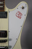 Close-up of the guitar's upper body, showing the white pickguard with a red bird graphic, a cream toggle switch, and chrome pickups.