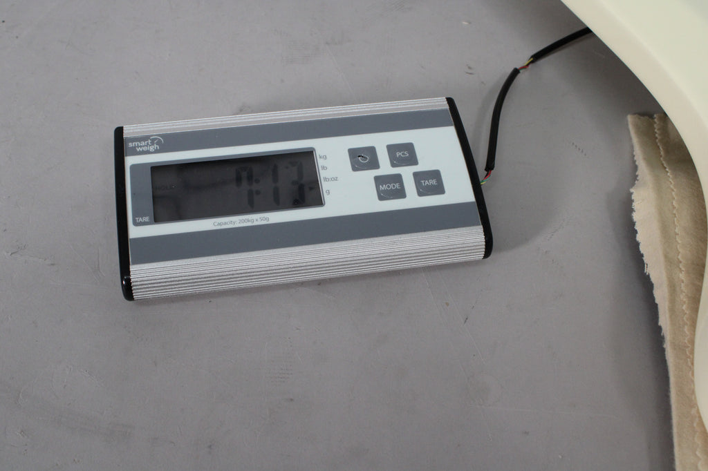 A digital scale displays "7.13" with a white guitar body partially visible on the right, resting on a cream-colored cloth.
