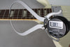A digital caliper measures the string height at the 12th fret of the white guitar, displaying "0.87" on its screen.