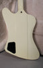 The back of an off-white guitar body with a black control cavity cover, showing a neck joint and strap button.