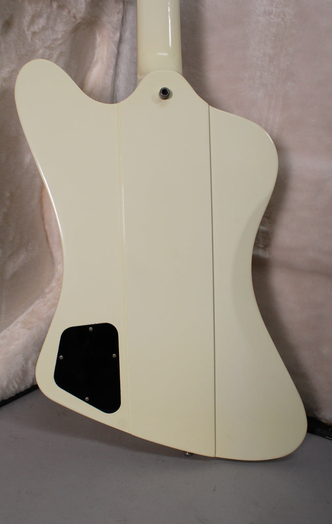 The back of an off-white guitar body with a black control cavity cover, showing a neck joint and strap button.