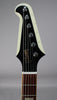 Close-up of the Firebird's headstock, showing the black face with gold lettering, chrome tuners, and a white binding.