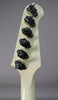 The back of an off-white headstock and neck, showing six chrome banjo-style tuners with some tarnishing around their bases.