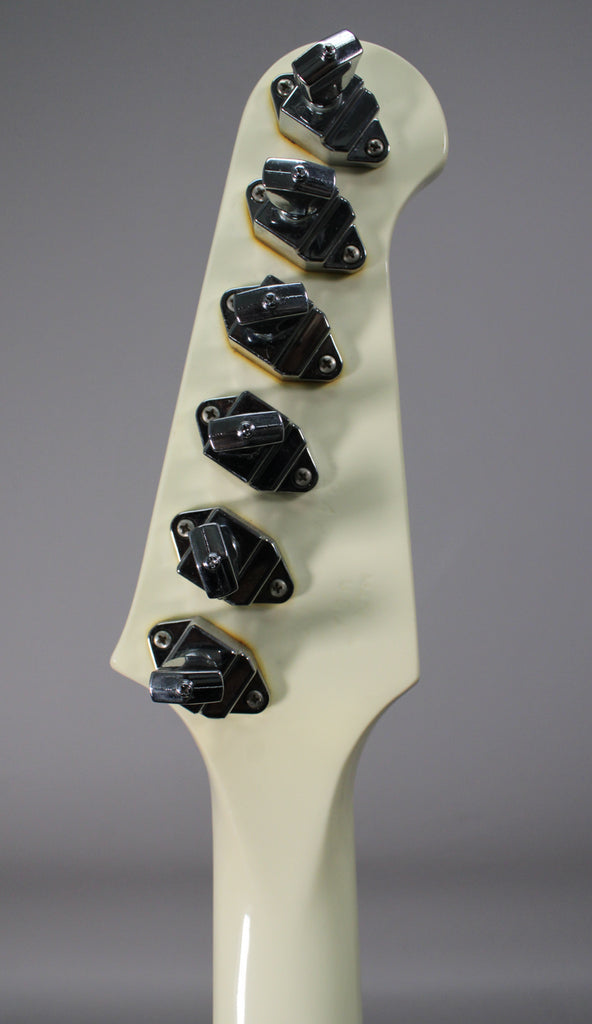The back of an off-white headstock and neck, showing six chrome banjo-style tuners with some tarnishing around their bases.