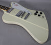 Angled view of an off-white electric guitar with chrome hardware, four black control knobs, and a white pickguard with a red bird graphic.