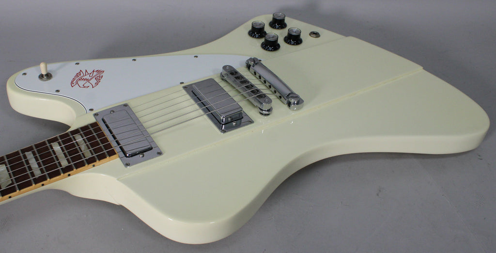 Upper body of an off-white electric guitar with a white pickguard, two chrome humbuckers, a tune-o-matic bridge, and four black control knobs.