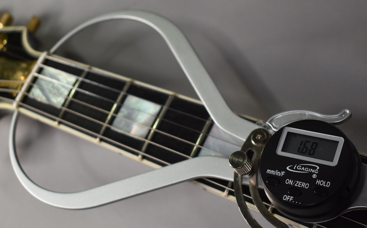 A digital fret height gauge shows 1.68mm on the guitar's ebony fretboard with mother-of-pearl block inlays.