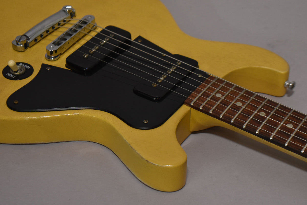 Close-up of the faded TV yellow double-cutaway body, showing the black pickguard, two P90 pickups, and a three-way toggle switch.
