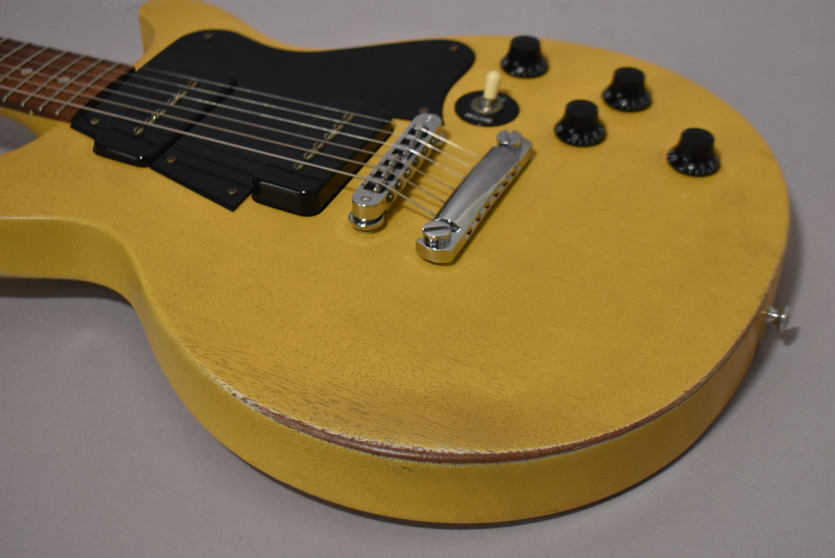 The guitar body, in faded TV yellow with a matte finish, shows wear along the edges, revealing the wood beneath.