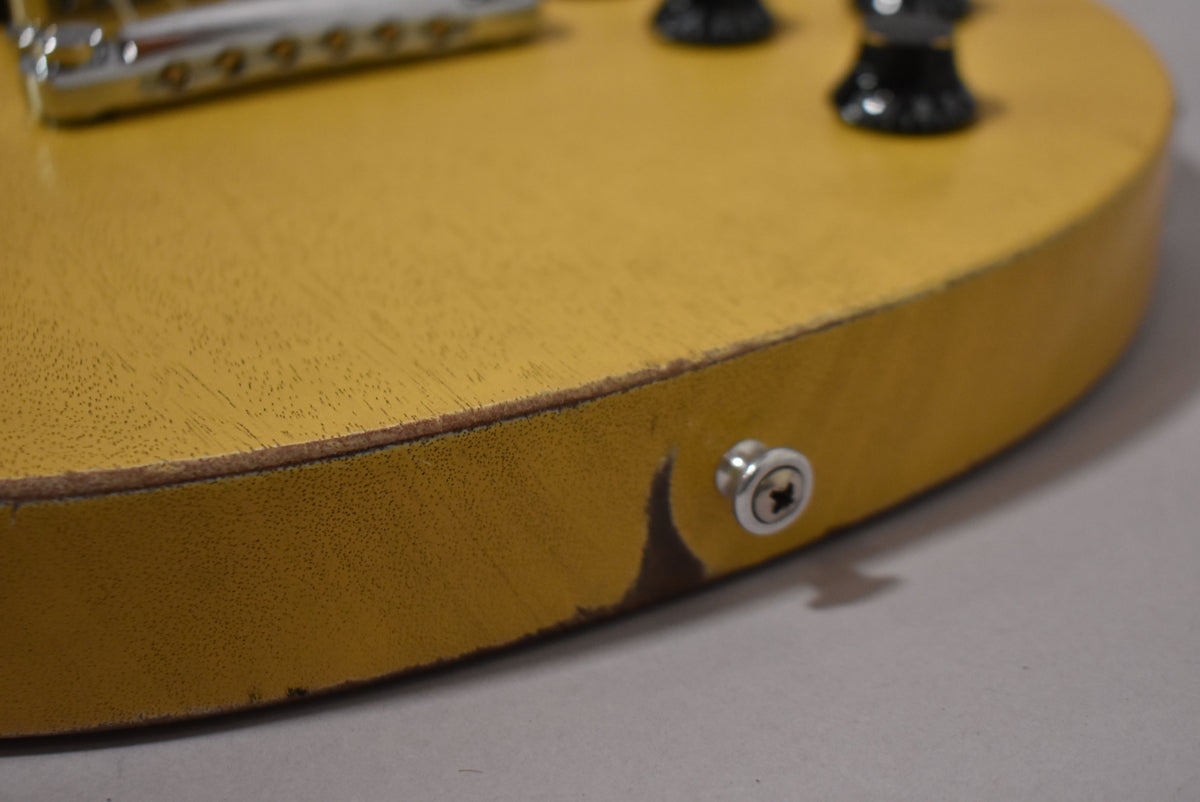 Close-up of the TV Yellow guitar body's lower bout, showing a strap button and significant finish wear and chipping on the edge.