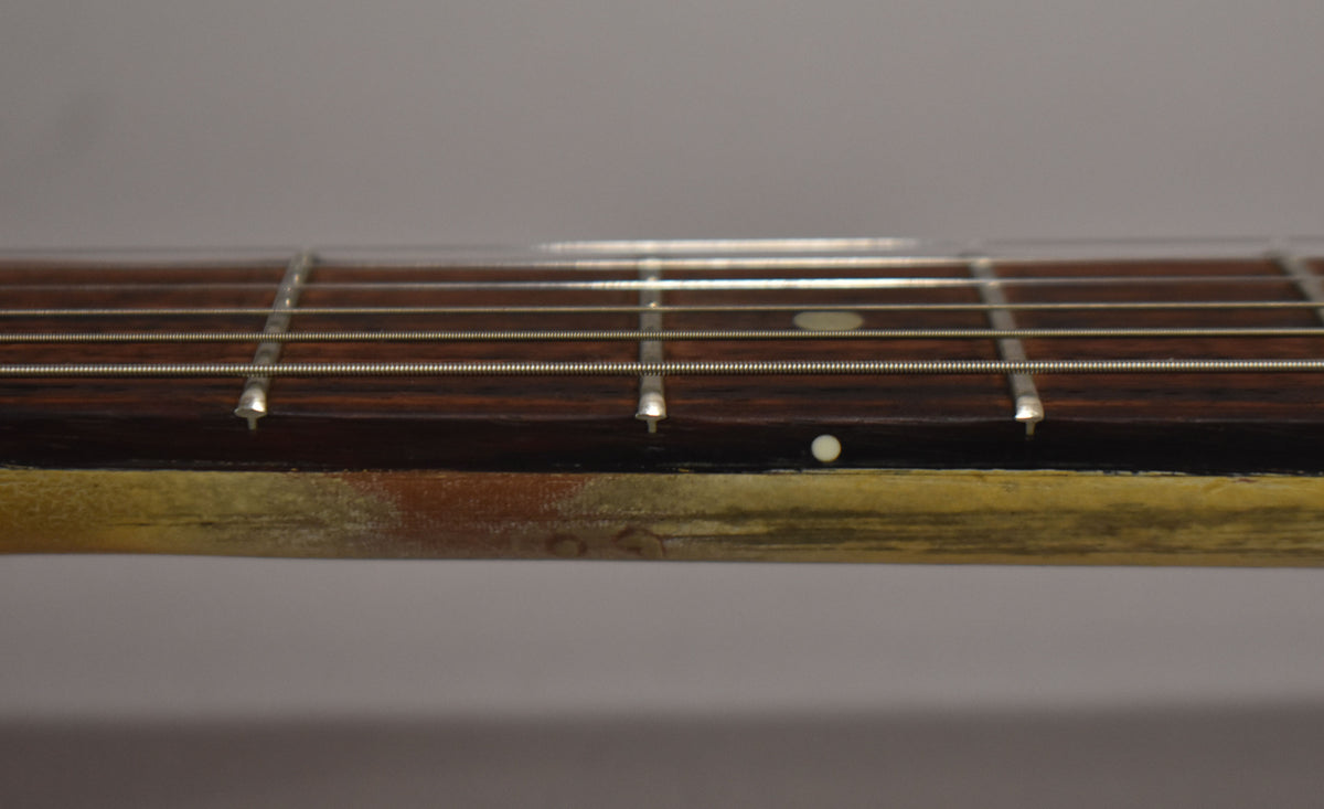 Close-up of the dark fretboard and strings, showing wear and discoloration on the faded TV Yellow finish along the neck's edge.