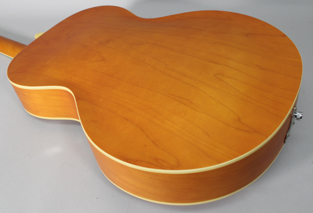 The back of the natural matte archtop guitar, showing light wood grain, cream binding, and a chrome endpin jack.