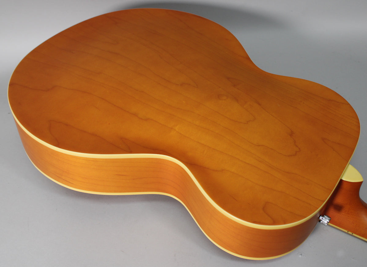 The guitar's natural matte finish back and sides are shown from above, with light wood binding and a strap button visible.