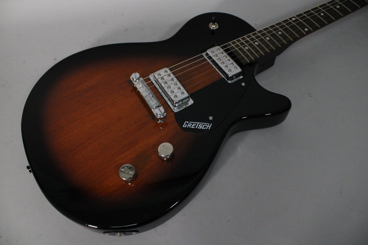 The tobacco sunburst electric guitar, angled from the upper right, shows its black pickguard, two chrome humbuckers, and two control knobs.