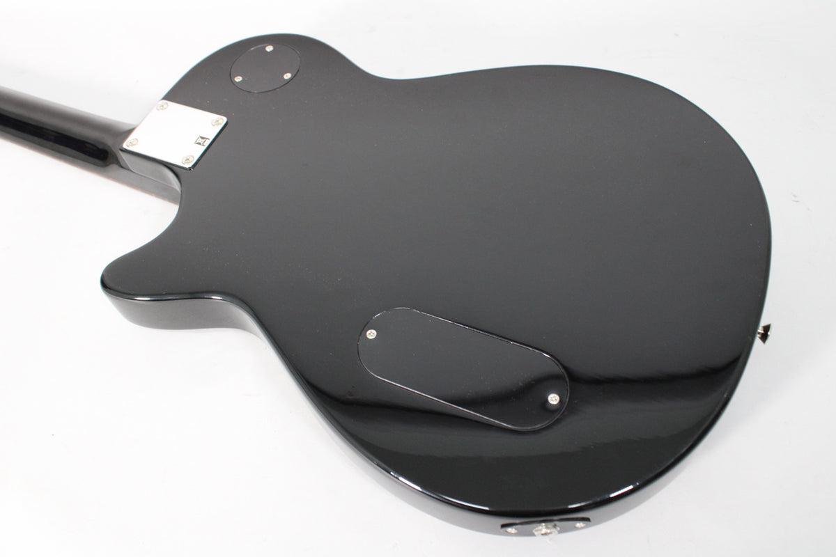 The back of a glossy black electric guitar, showing the neck joint, control cavity cover, and input jack.