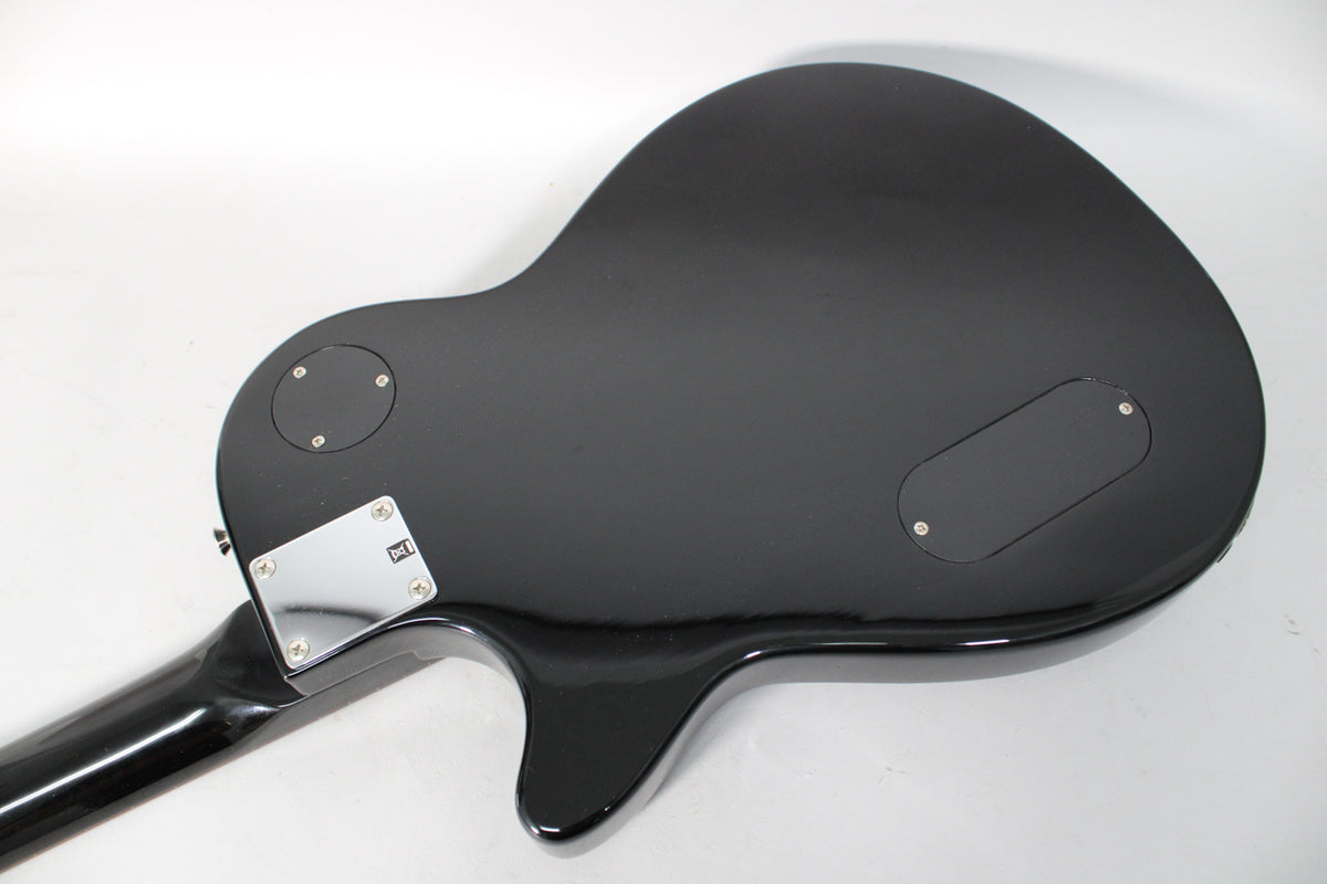 The guitar's glossy black back, showing the neck joint, control cavity covers, and some light surface scratches.