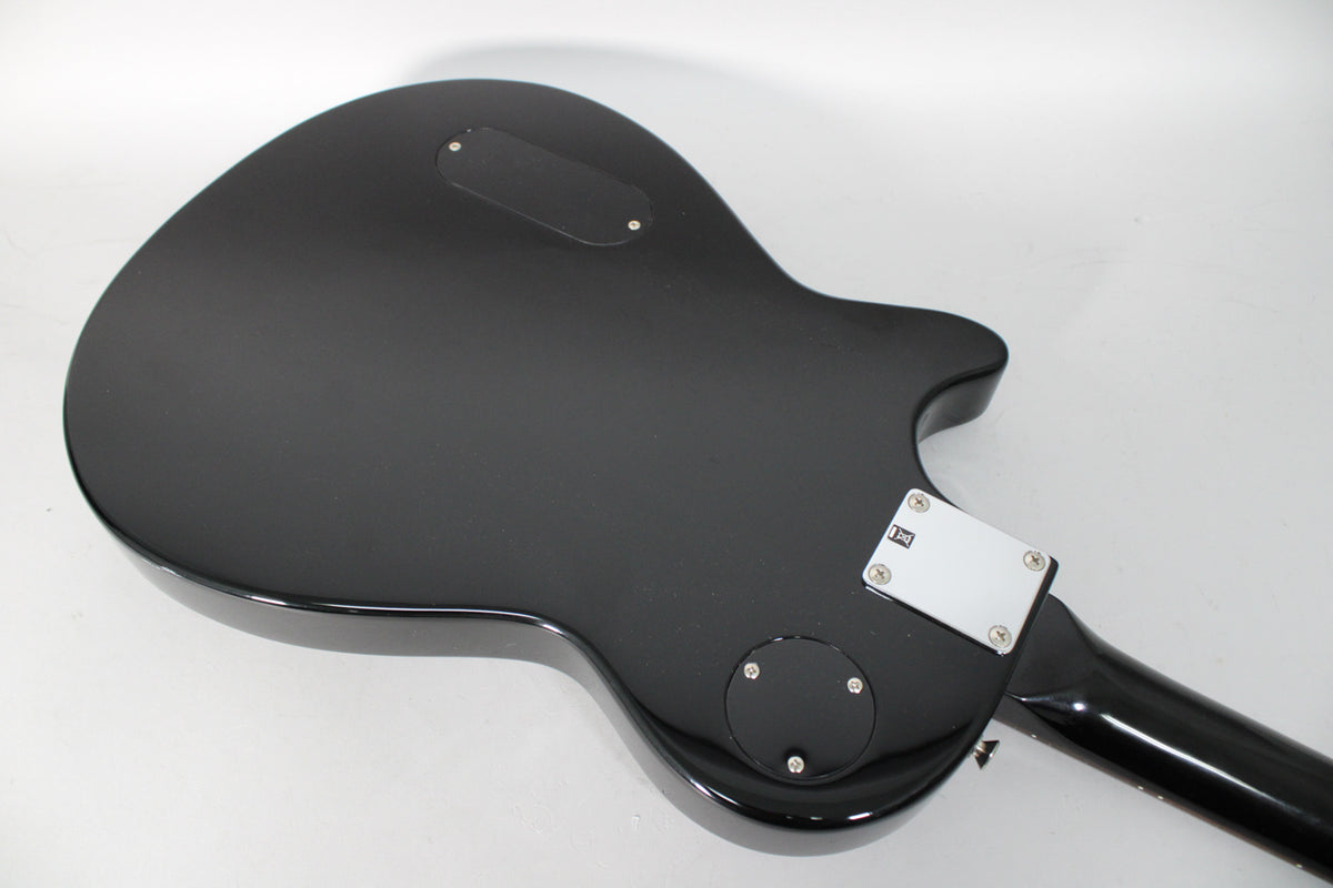 The guitar's matte black back, angled from the lower left, shows a rectangular control plate, a round plate, and a chrome neck plate.