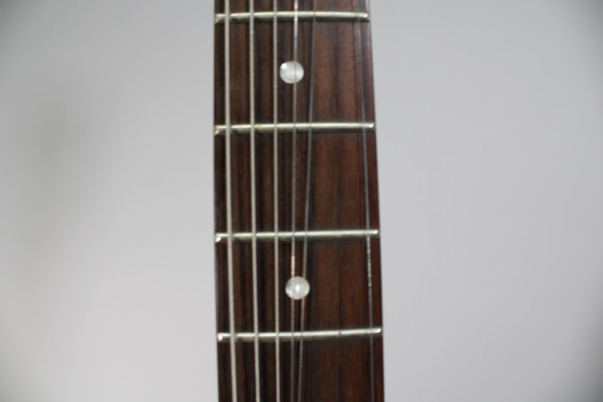 Close-up of the guitar's dark brown fretboard with silver frets and two white dot inlays, viewed from above.
