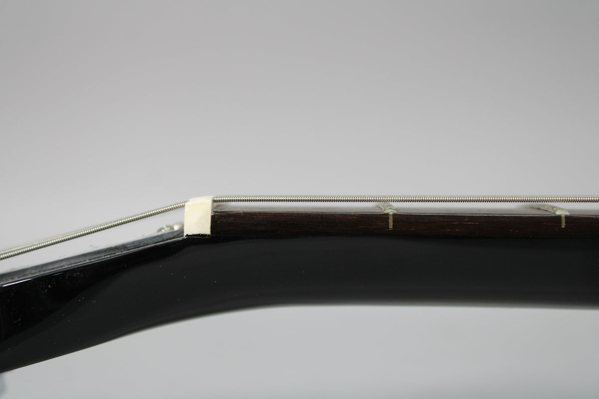 Close-up of the guitar's nut and first few frets, showing the dark fretboard, light nut, and a few small dings on the neck.