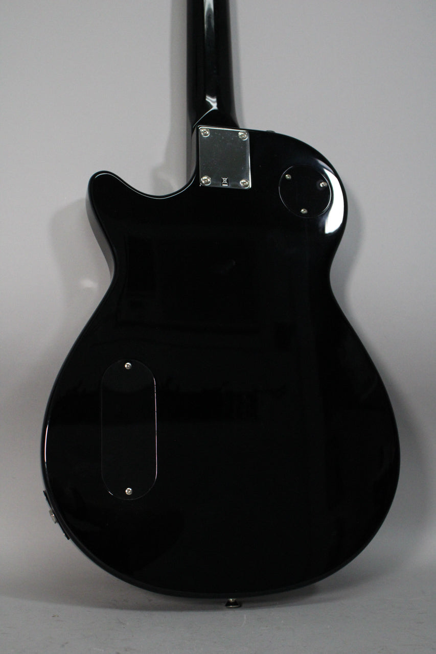 The back of a black electric guitar, showing the neck joint, control cavity cover, and output jack.