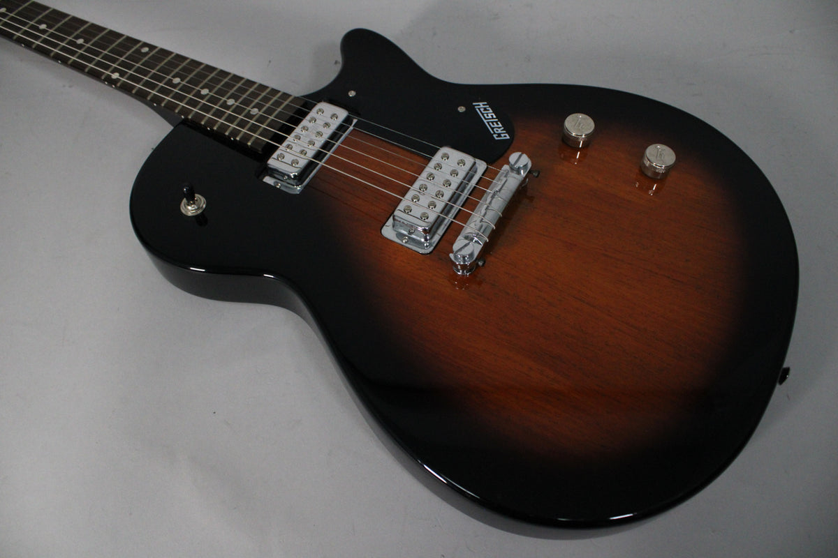 The tobacco sunburst electric guitar, angled from the left, features two chrome humbuckers, a black pickguard, and two control knobs.