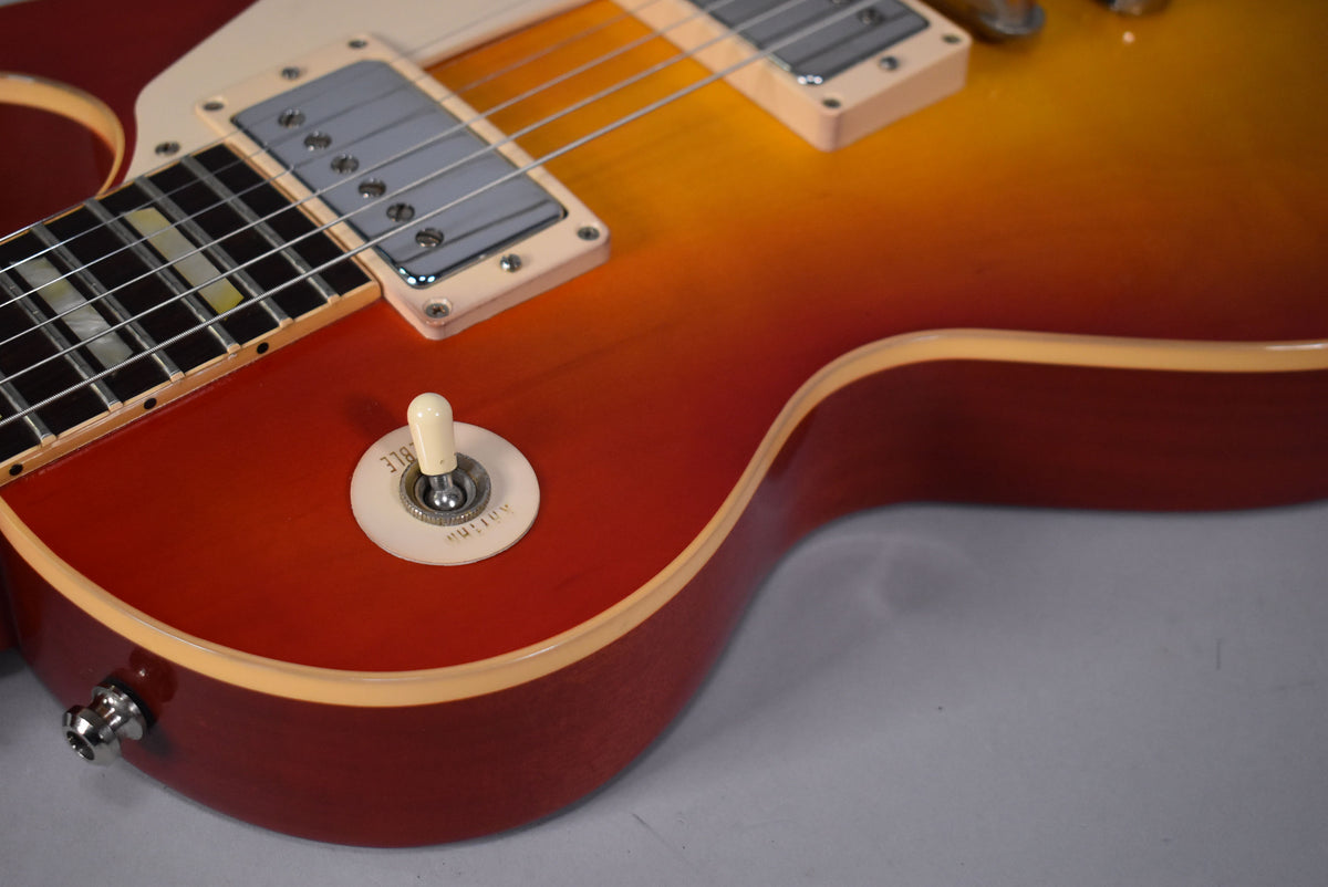 Close-up of the cherry sunburst body, showing the cream pickup rings, chrome bridge pickup, and cream toggle switch with "Rhythm" visible.