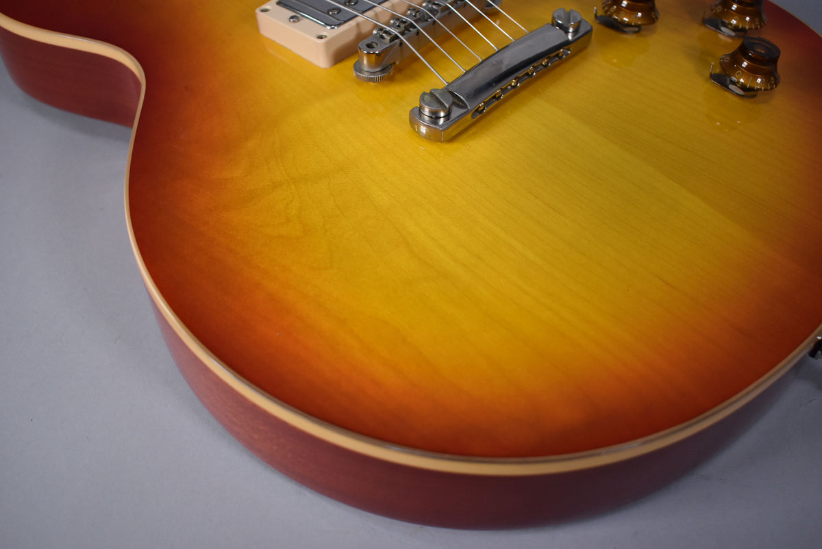 Close-up of the guitar's lower bout, showing the cherry sunburst finish, bridge, cream pickup ring, and two amber control knobs.