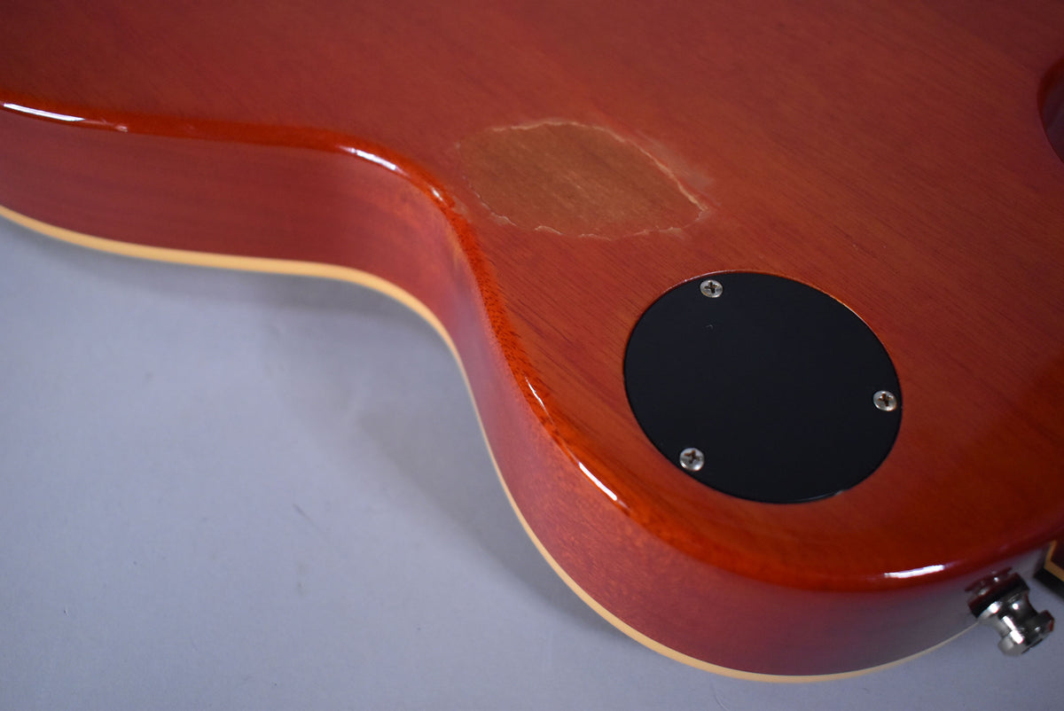 Close-up of the guitar's cherry sunburst back, showing a large area of finish wear near the black control cavity cover.